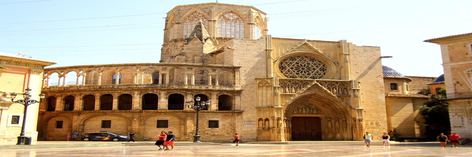 Cathedral featuring a tall tower and clock tower, situated in the vibrant Plaza de la Virgen.