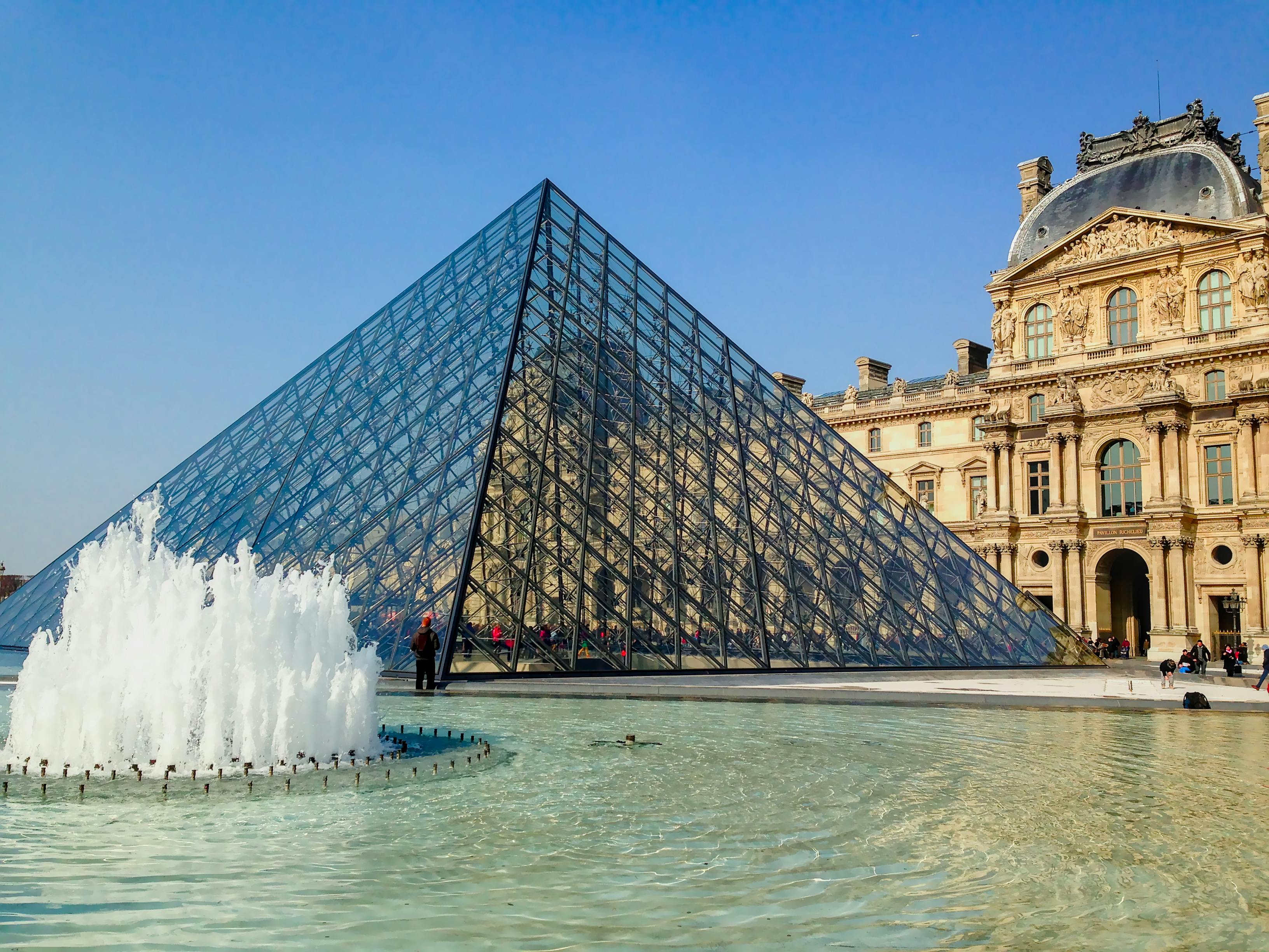The Louvre Museum in Paris, France, showcasing its iconic glass pyramid and historic architecture.
