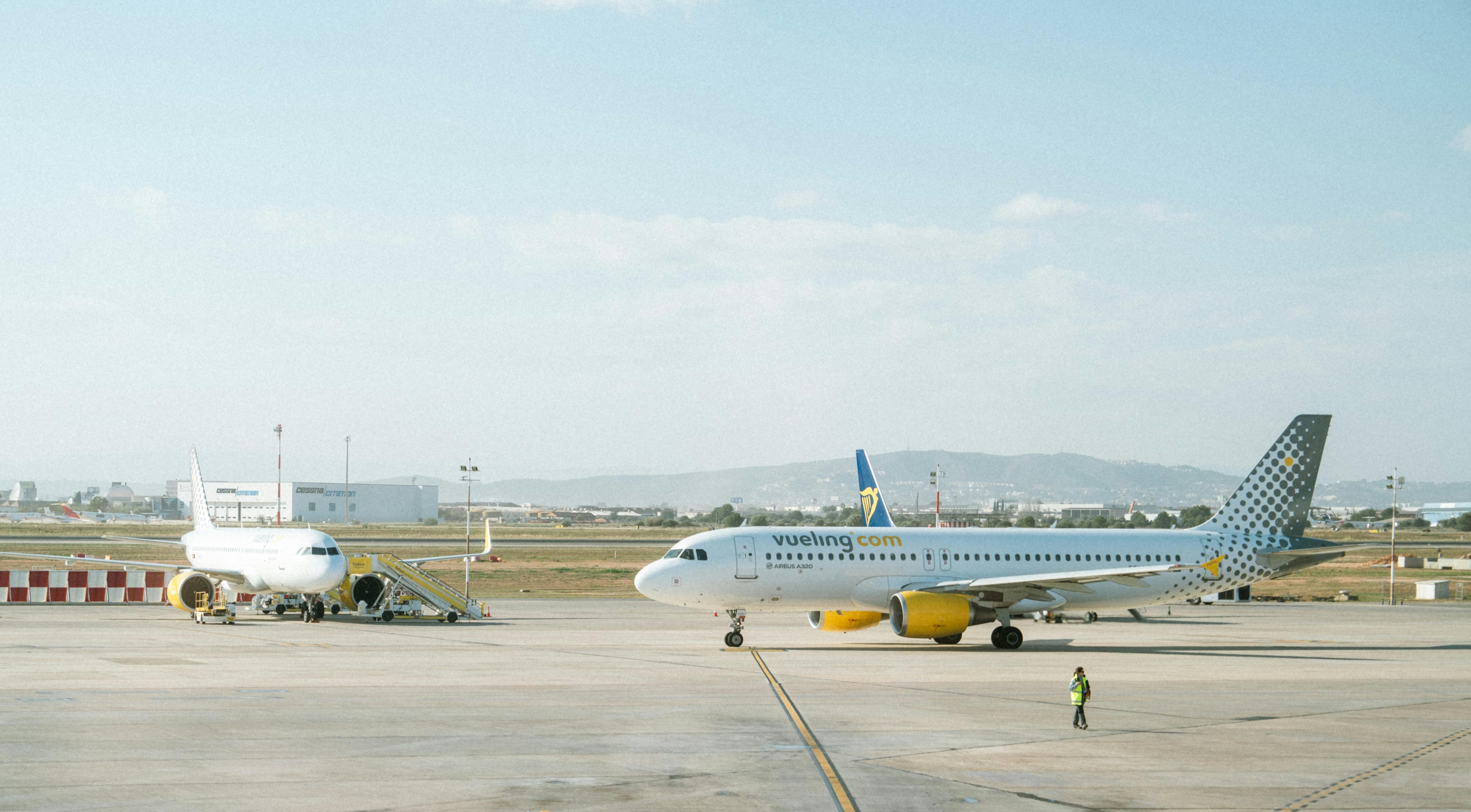 Two airplanes parked on the runway at Barcelona Airport, showcasing a clear blue sky in the background.