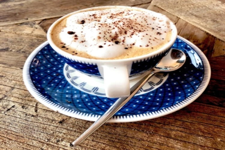 A blue and white cup topped with a spoon, symbolizing the finest coffee experience in Canberra.