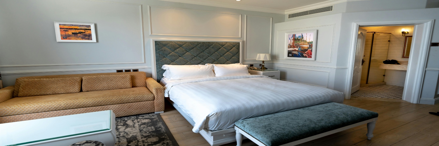 A hotel room in Canberra featuring a bed, a couch, and a decorative painting on the wall.