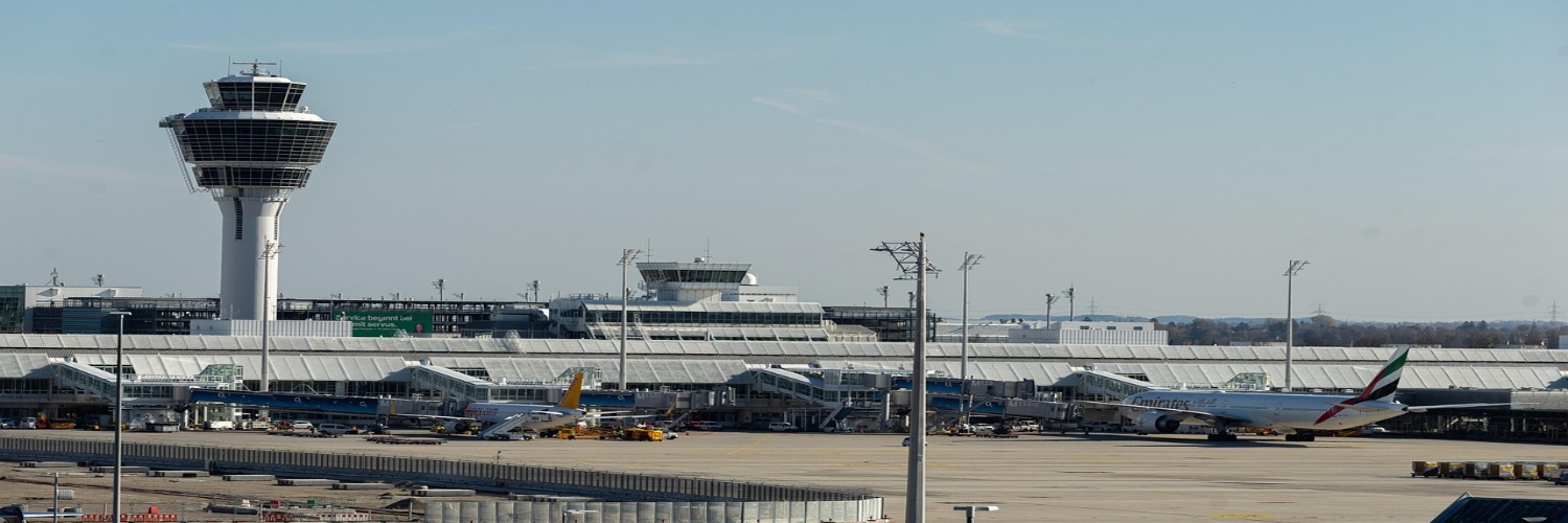 A plane resting at Dubai Airport, surrounded by airport facilities and a clear, sunny atmosphere.