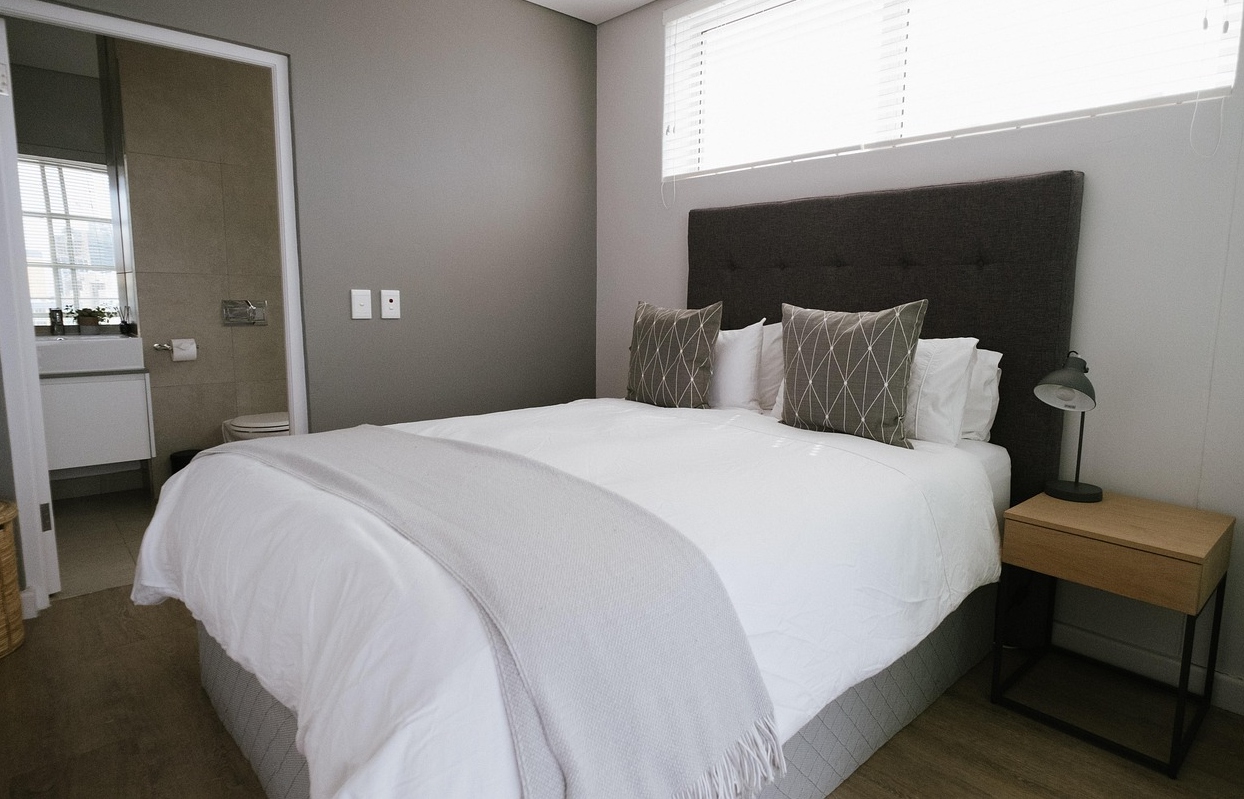 Stylish bedroom with a bed, nightstand, and window, highlighting top luxury room options in Canberra.