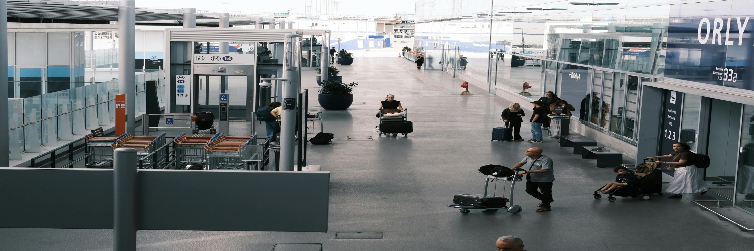 People walking with luggage through the bustling terminal of Paris Airport.