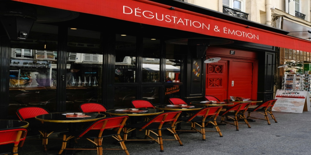 A restaurant in Paris with red chairs and tables outside, reflecting the city's renowned culinary culture.