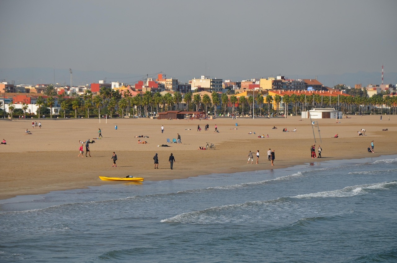 A sunny sandy beach in València, showcasing the best beach season with clear skies and gentle waves.