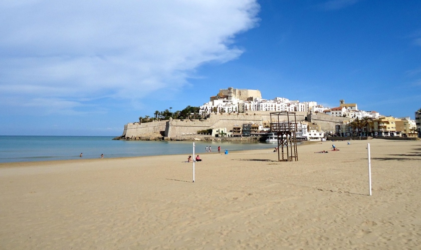 A beautiful beach in Valencia with a castle looming in the background, recognized as one of the top beach destinations.