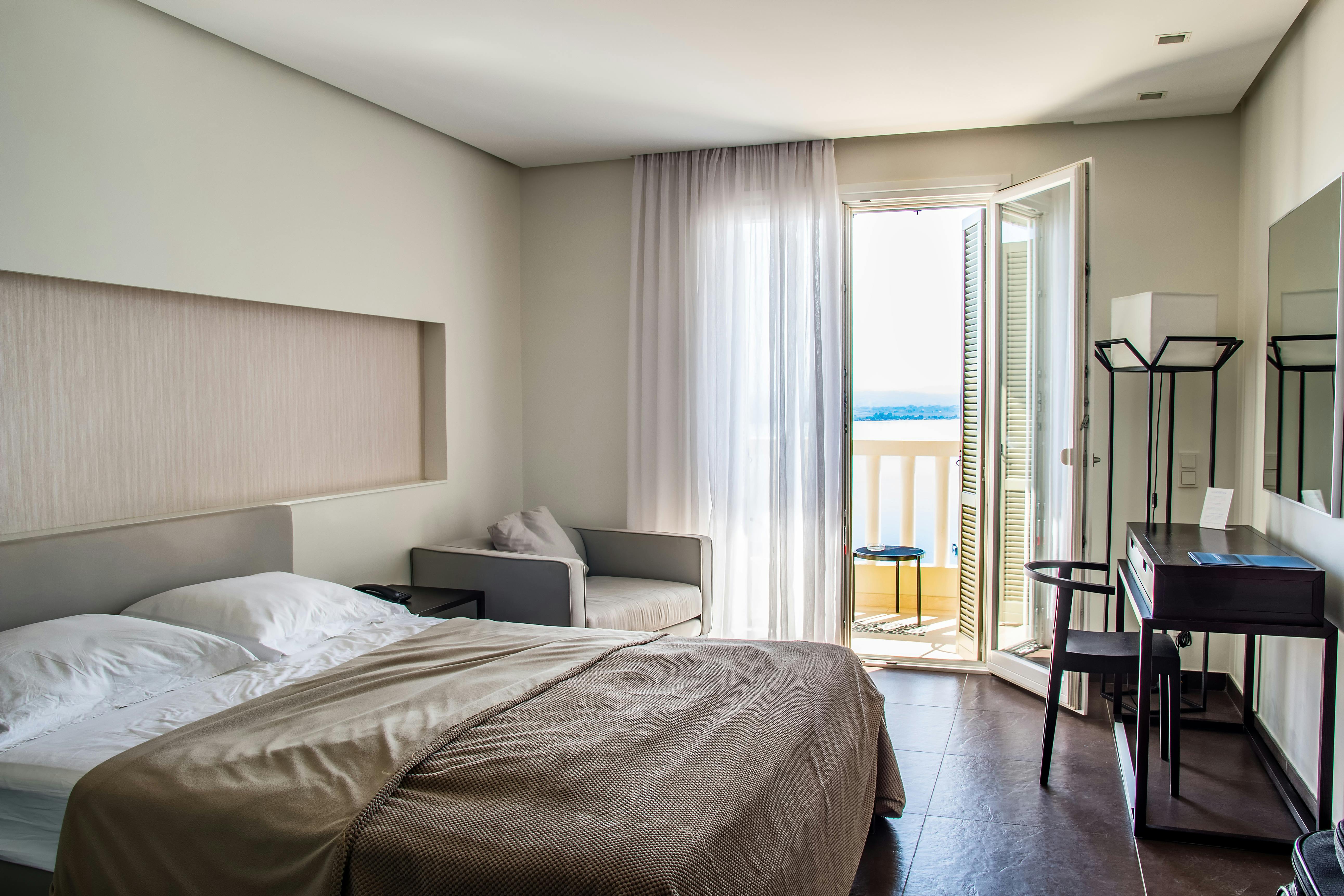 Elegant hotel room with a comfortable bed and a balcony, showcasing the best stay in Canberra.