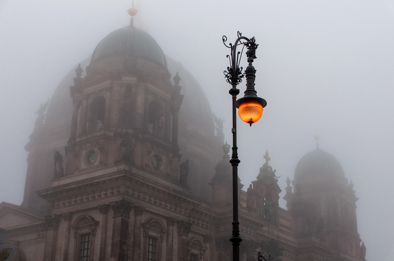 A street light on a pole stands in front of the Berlin Dome, surrounded by a winter landscape.
