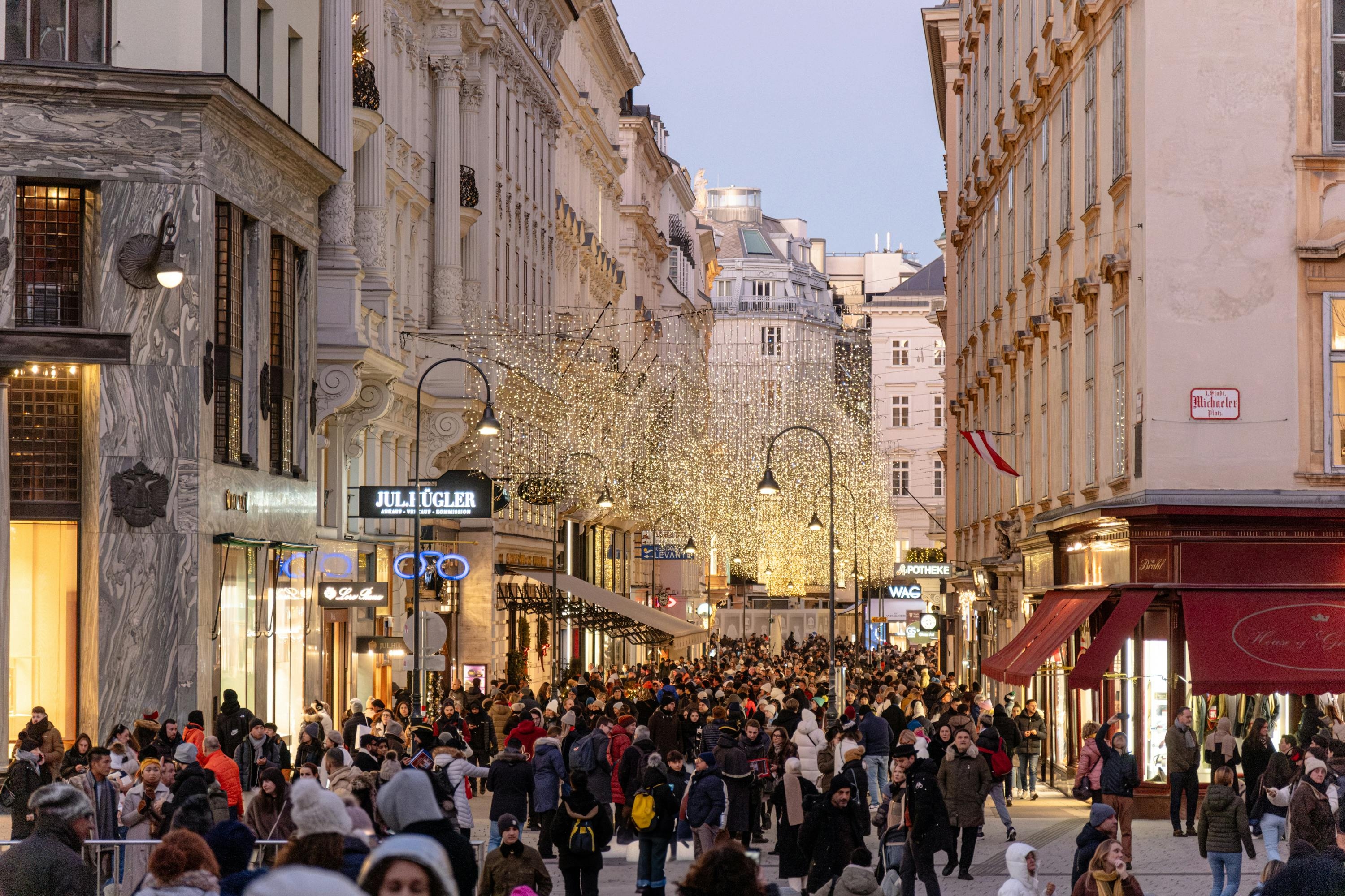 A festive Christmas market in Vienna, Austria, adorned with lights and bustling with people enjoying the holiday atmosphere.