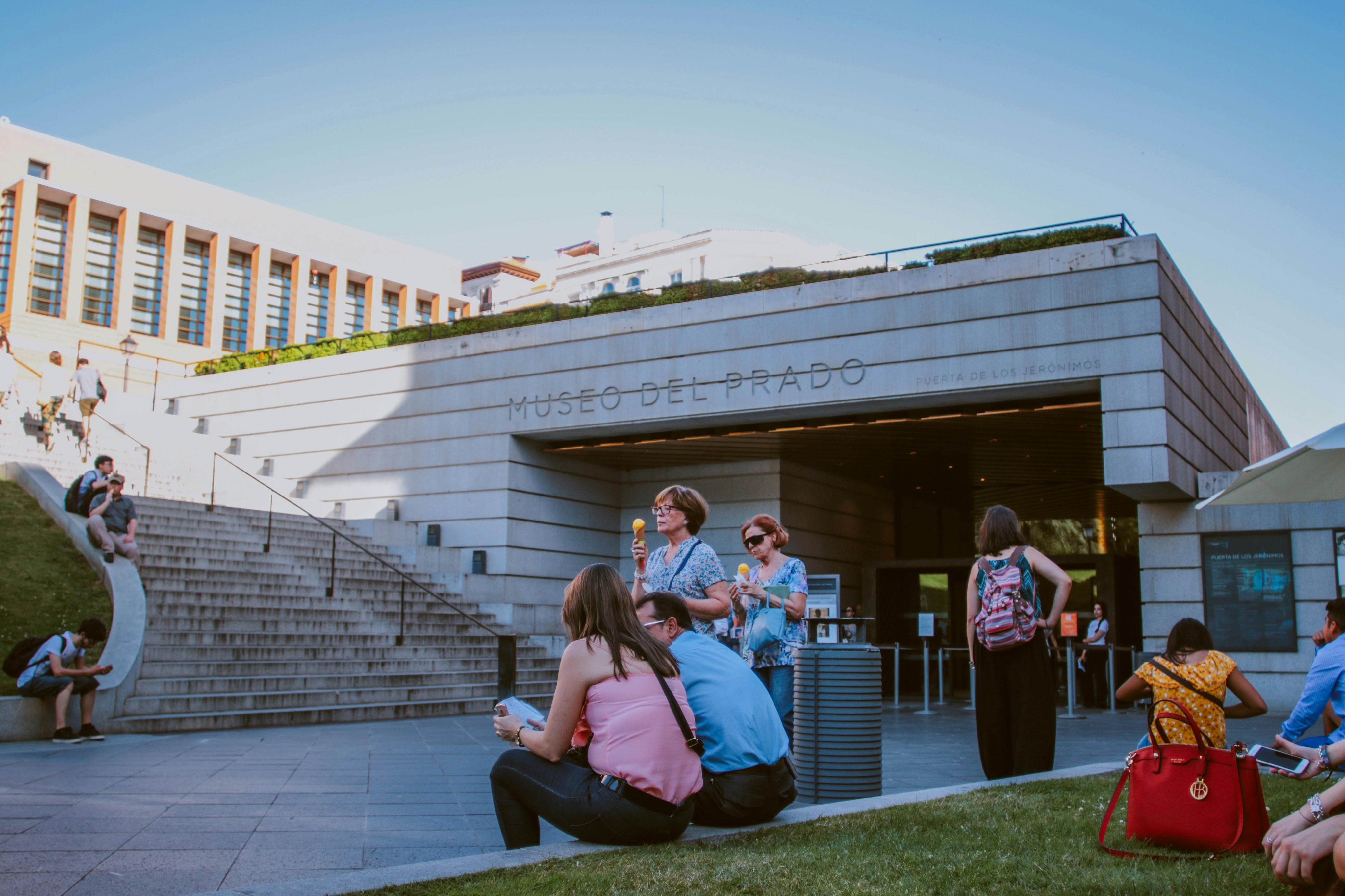 A group of people relaxing on the grass outside the University of Sydney, enjoying a sunny day.