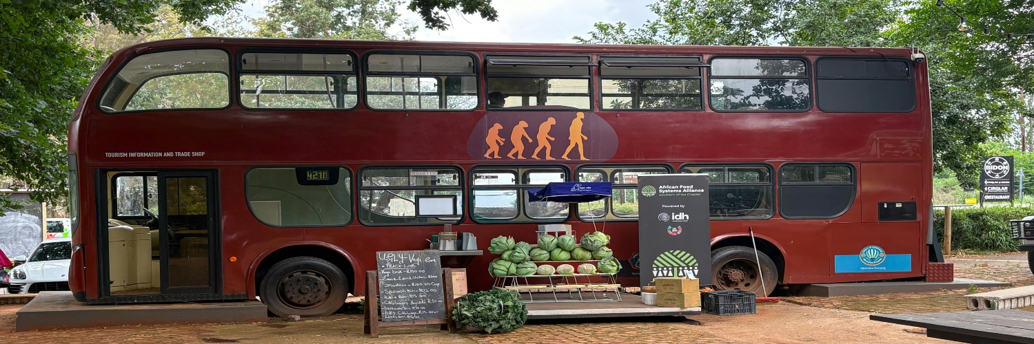 A retro double-decker bus converted into an outdoor café, featuring a sign that reads "the bus that goes everywhere.
