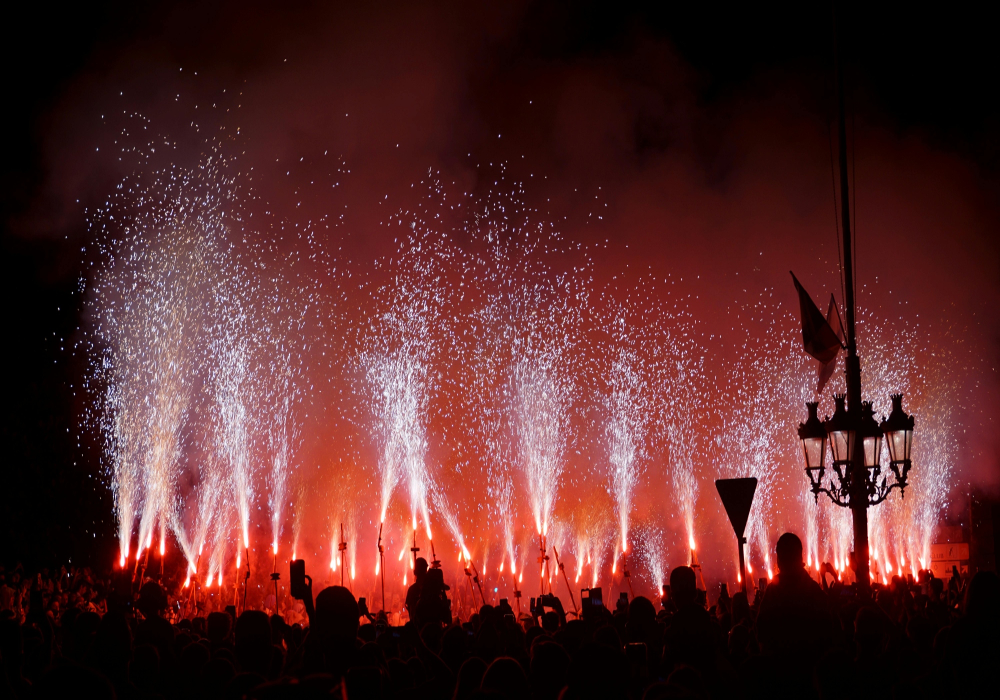 Colorful fireworks burst over a lively crowd, marking the grand finale of the Night Fireworks Festival in Reus.