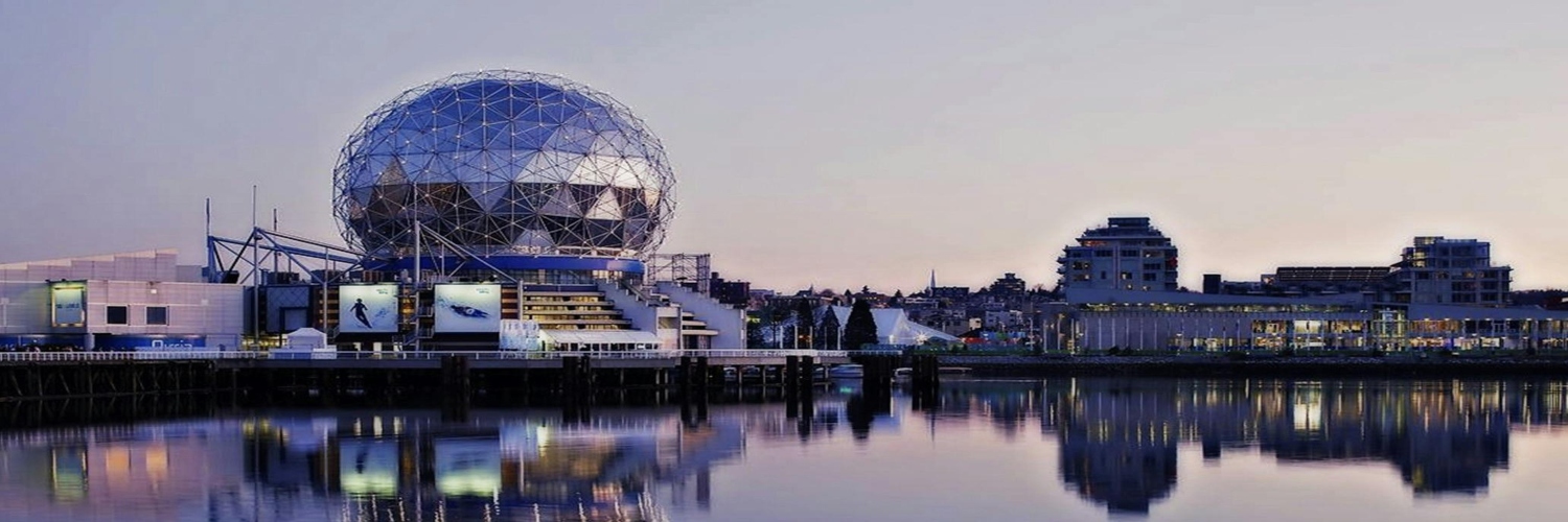 Grey dome building reflected in water at dusk, with a vibrant sunset sky in Vancouver, Canada.