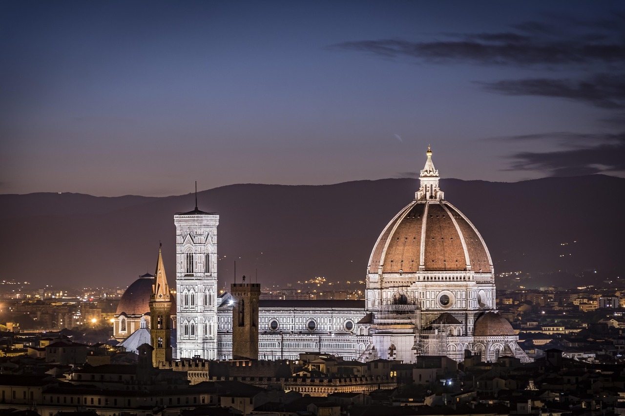 Panoramic view of Florence from a hilltop, showcasing the Cathedral and cityscape under a clear blue sky.