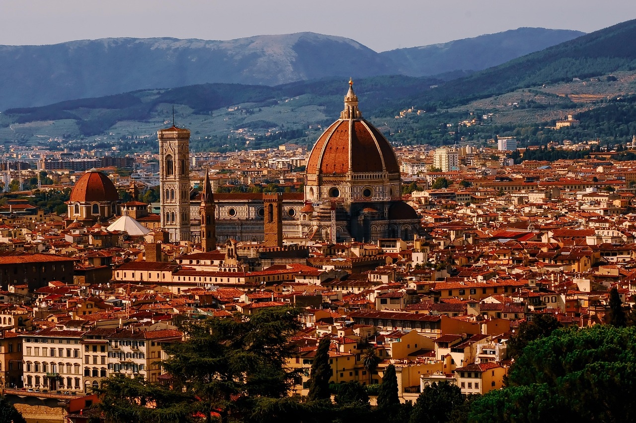 The city of Florence, Italy, bathed in summer sunlight, featuring its renowned landmarks and lively streets.

