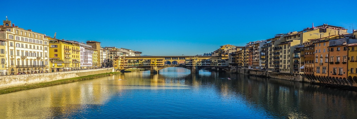 The famous Ponte Vecchio bridge crosses the Arno River in Florence, Italy, featuring picturesque architecture and bustling shops.