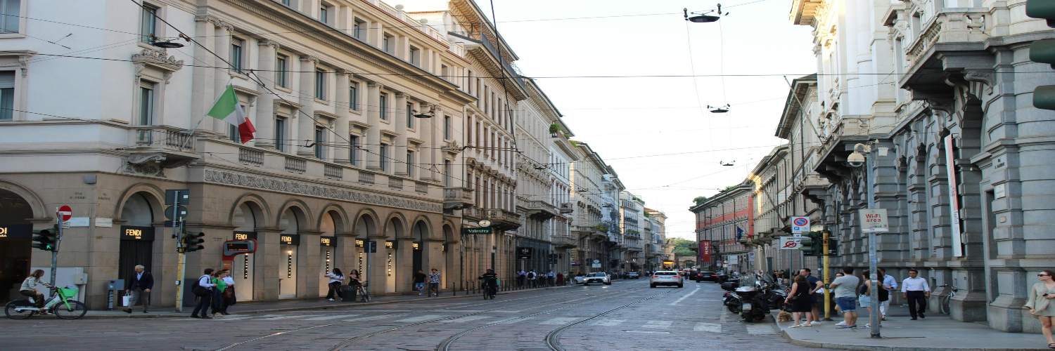 Bustling Milan street featuring historic buildings and numerous pedestrians enjoying the lively atmosphere.