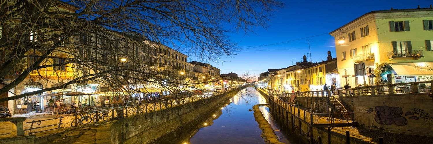 A scenic canal in Milan, bustling with tourists enjoying a day of sightseeing.