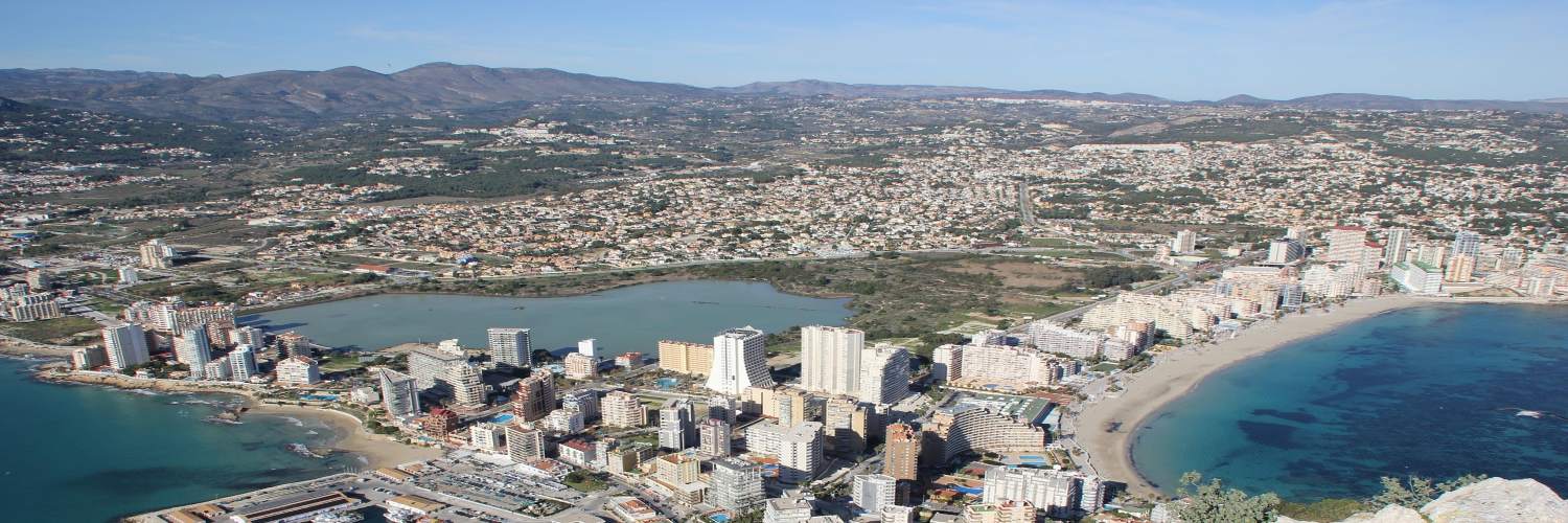 Panoramic view from the top of a mountain in Alcudia, Spain, showcasing lush landscapes and distant coastline.