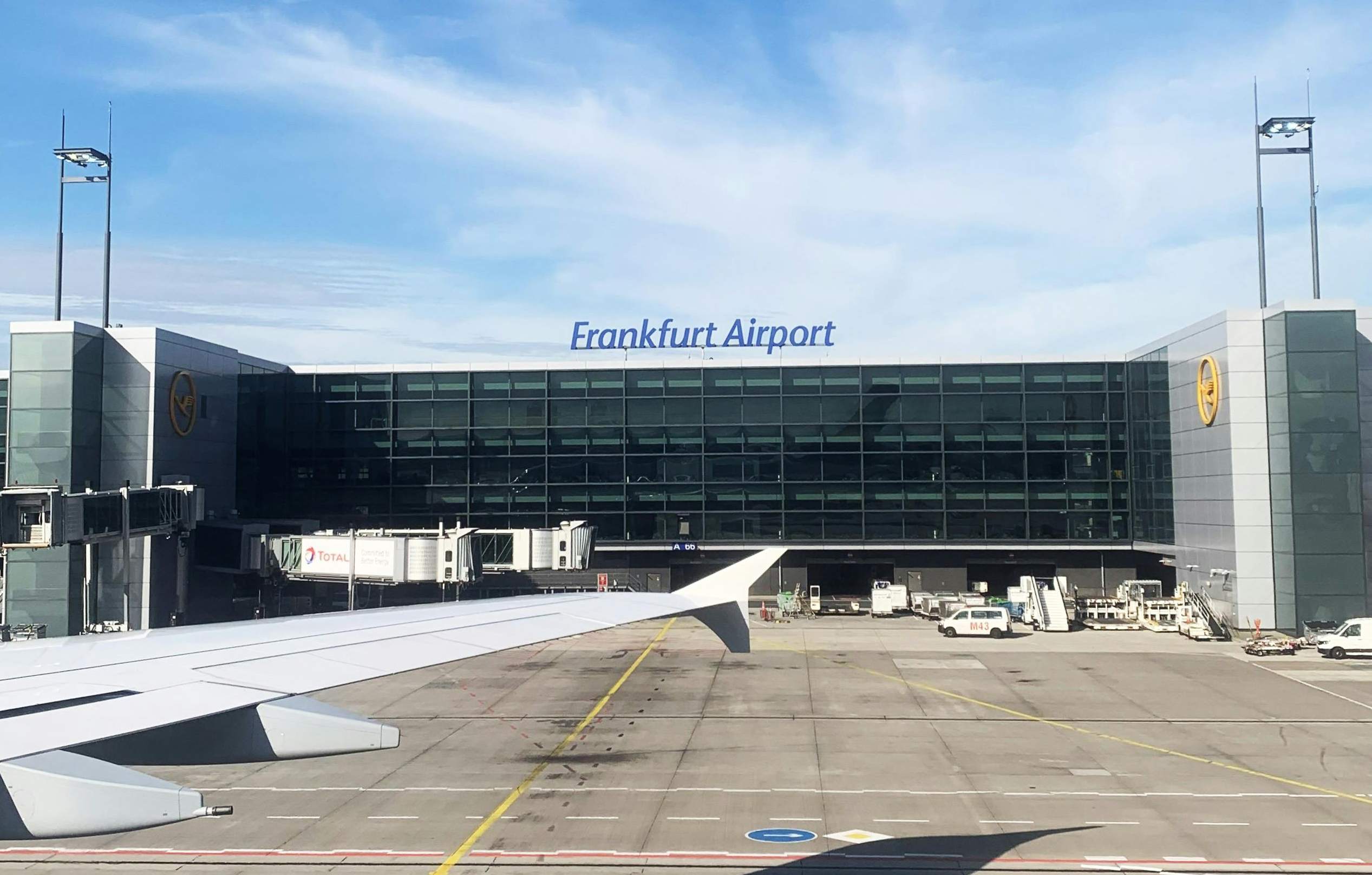Airplane wing seen from a window at Frankfurt Airport Terminal 2, showcasing the airport's bustling atmosphere.