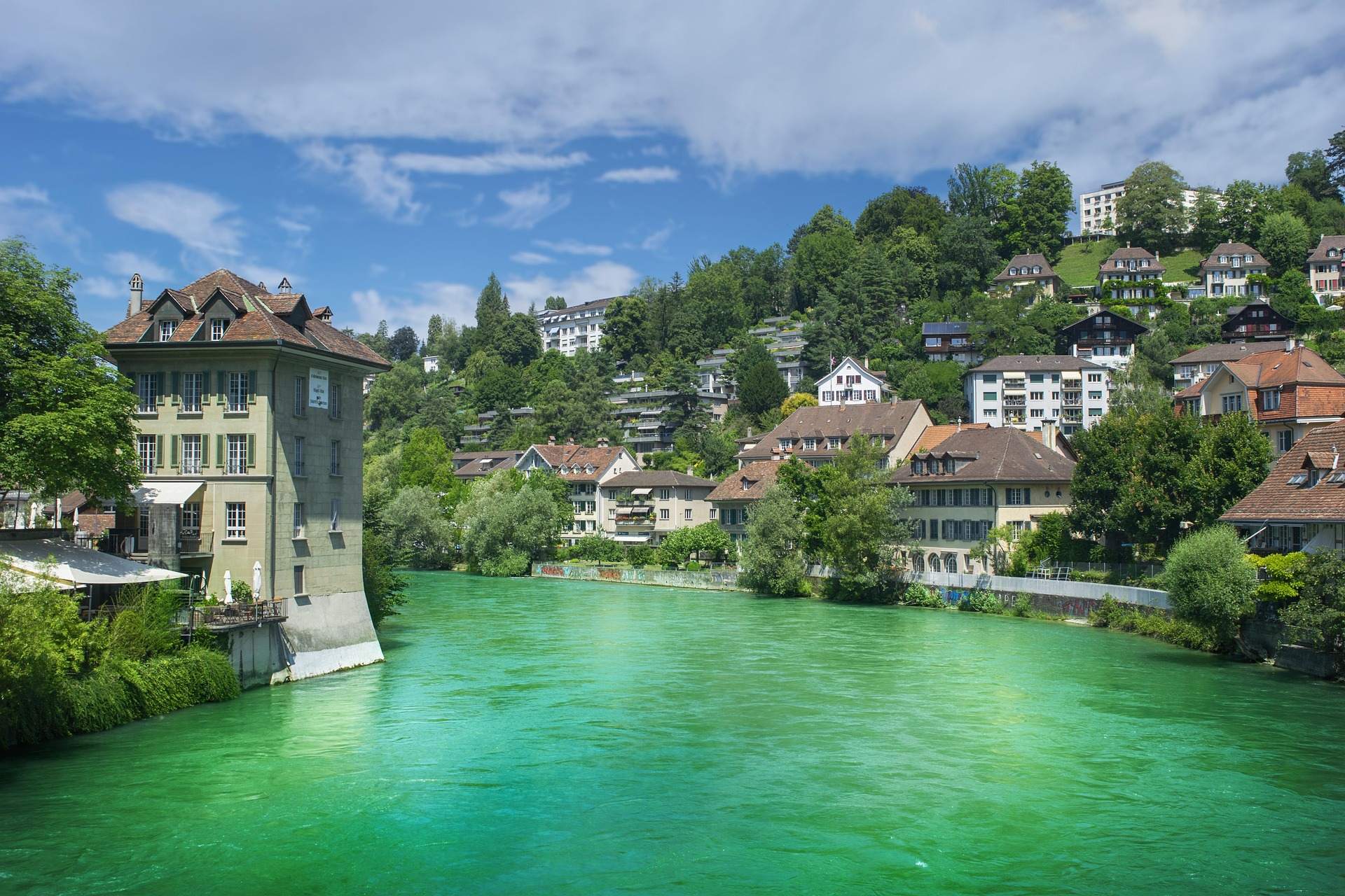 Overhead perspective of Bern, featuring its charming buildings and green spaces, emphasizing its worth as a tourist spot.