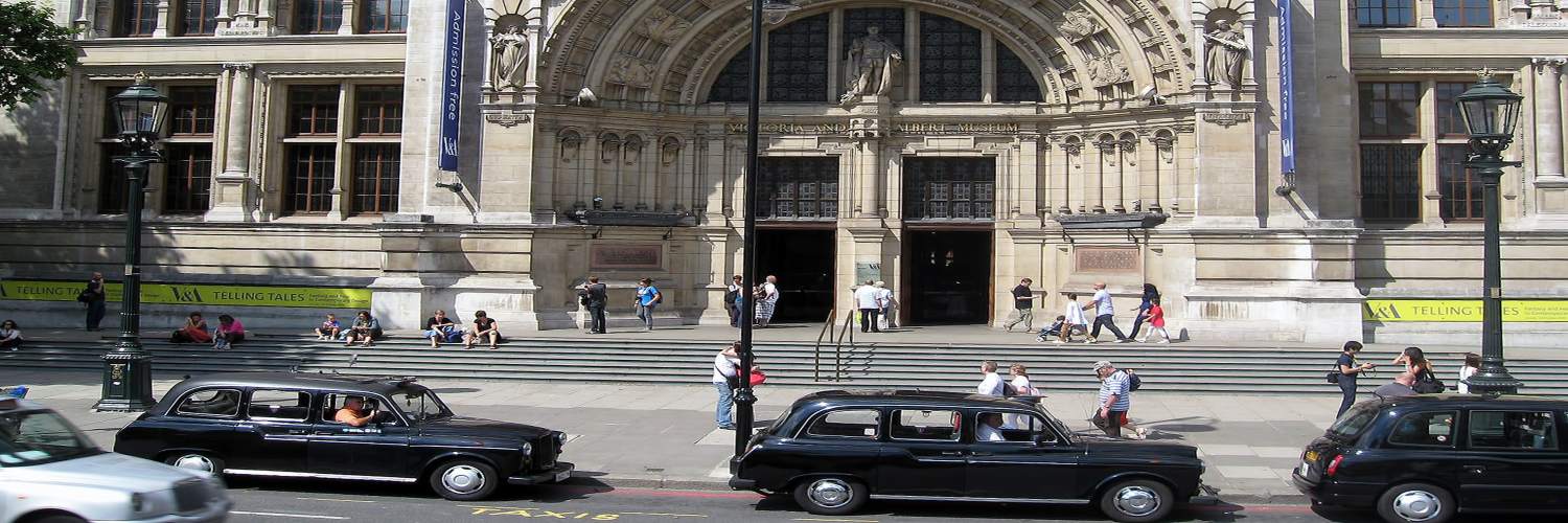 A large building featuring a clock tower, seen from a London airport taxi.