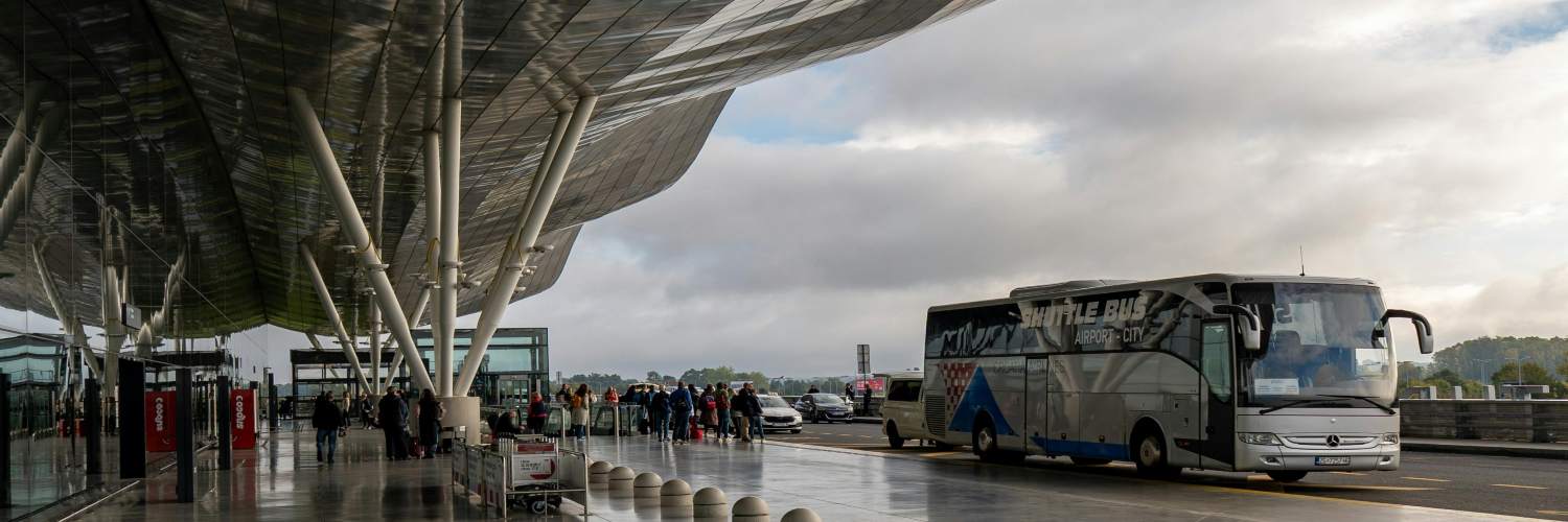A parked airport shuttle bus at the terminal, ready to transport passengers to and from flights.