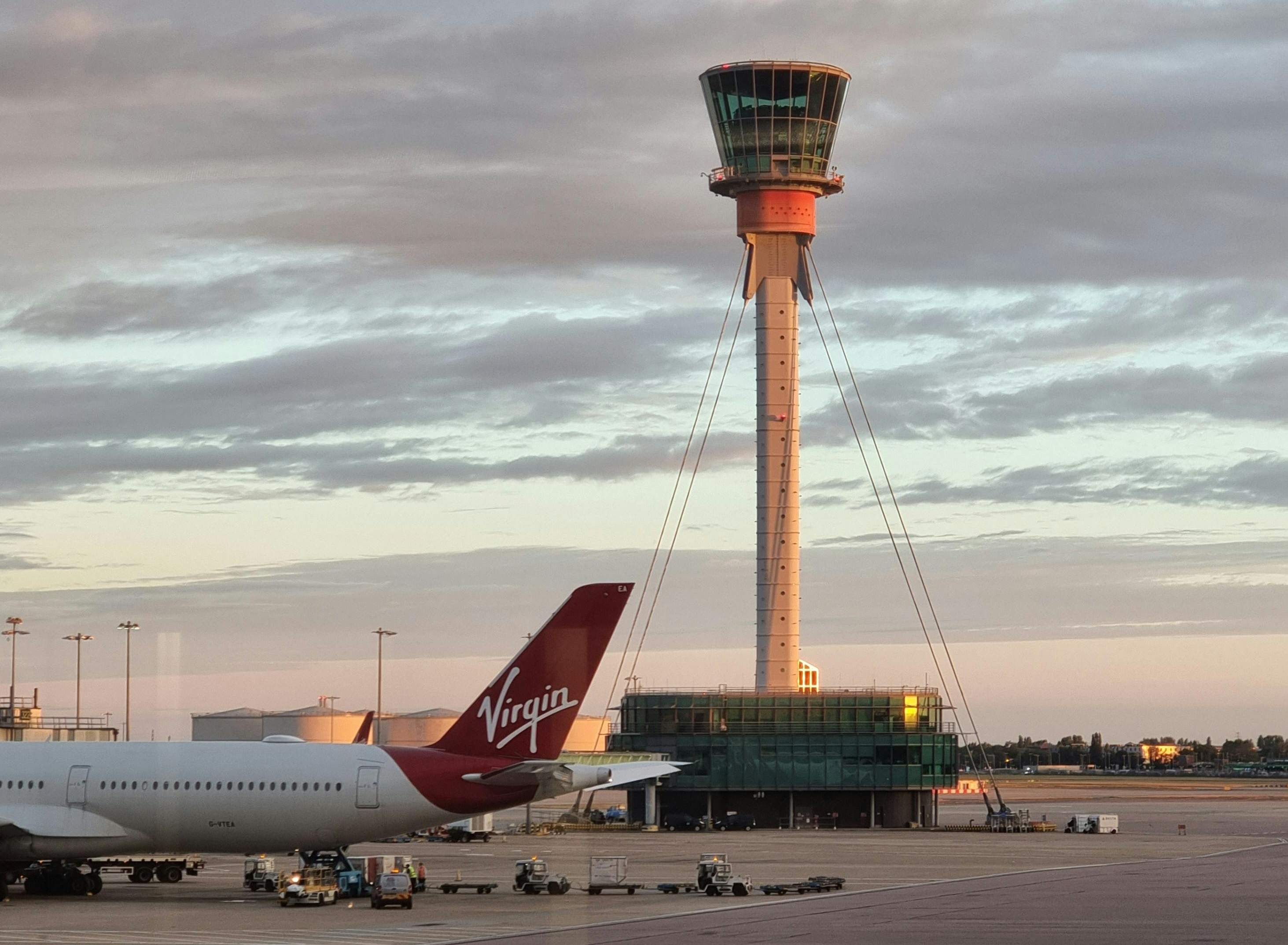 An airplane stationed at an airport, with a control tower rising in the background, highlighting air travel facilities.
