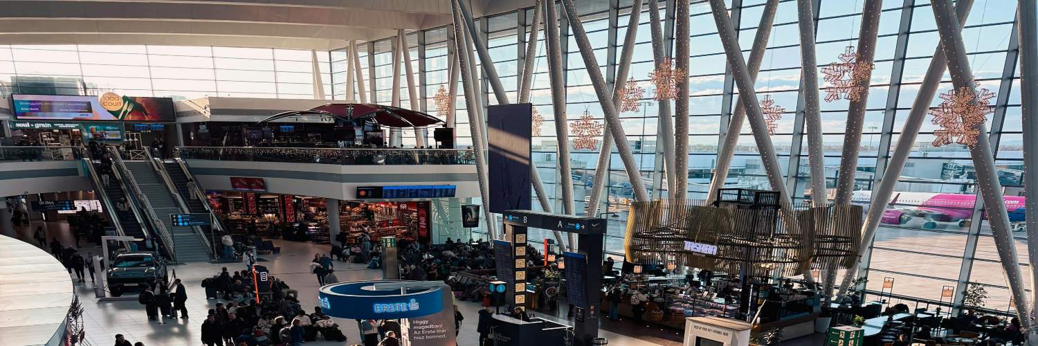 Inside Brussels Airport, showcasing people walking around the terminal, with signs and shops visible throughout the space.