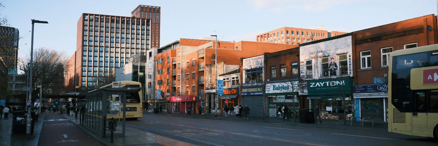 A Manchester city street scene with a bus and surrounding buildings, highlighting the bus transfer system in the area.