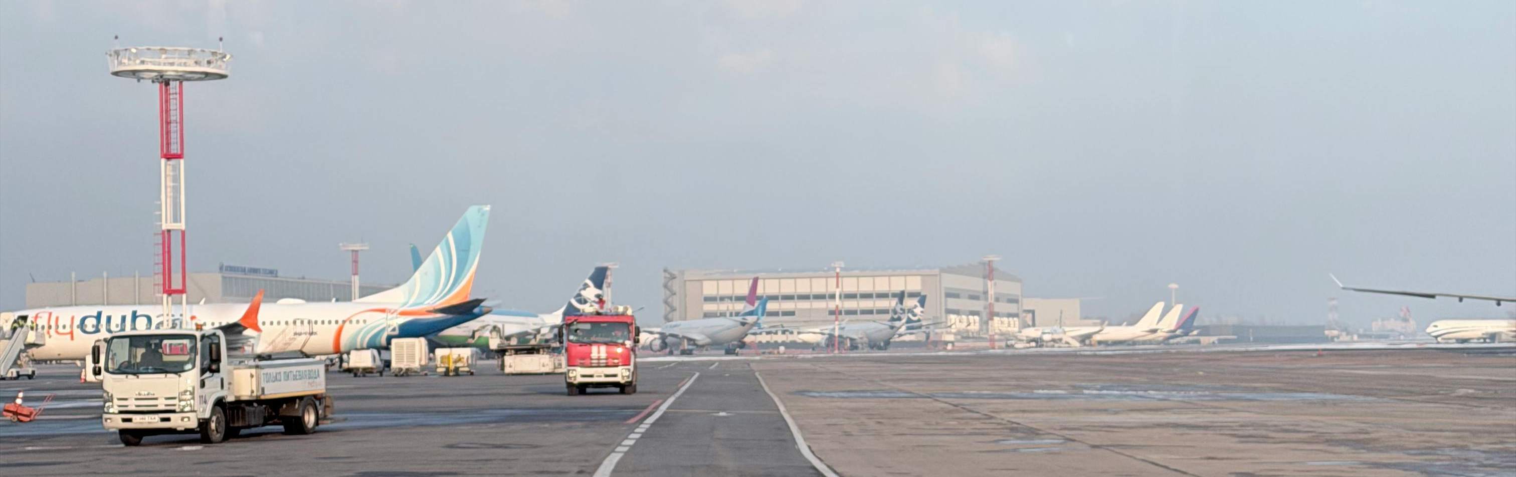 Orly Airport parking lot in Paris, featuring several airplanes parked on the tarmac under a clear blue sky.