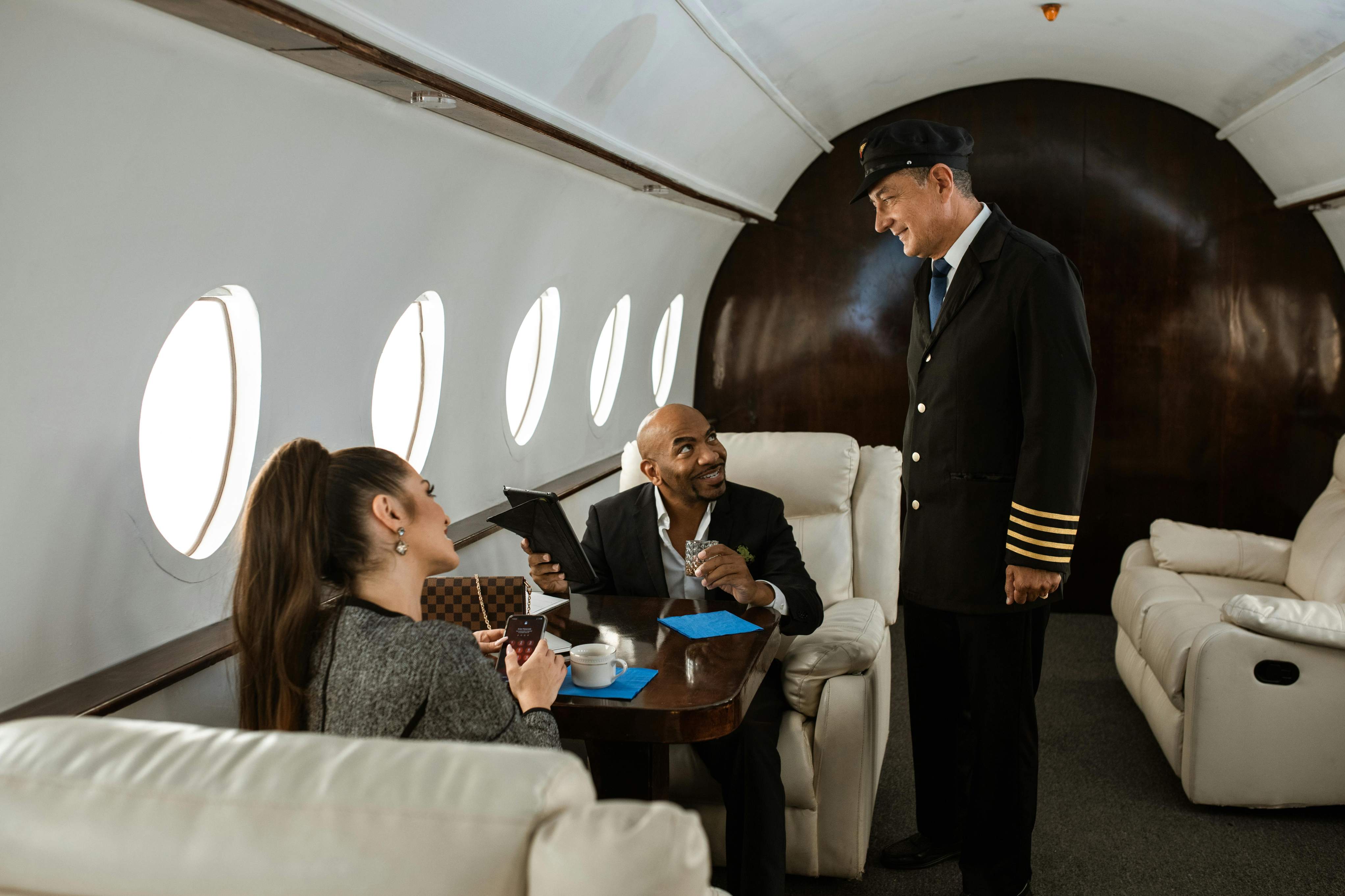 A man and woman seated in a private jet, dressed in business attire, preparing for their flight as business travelers.