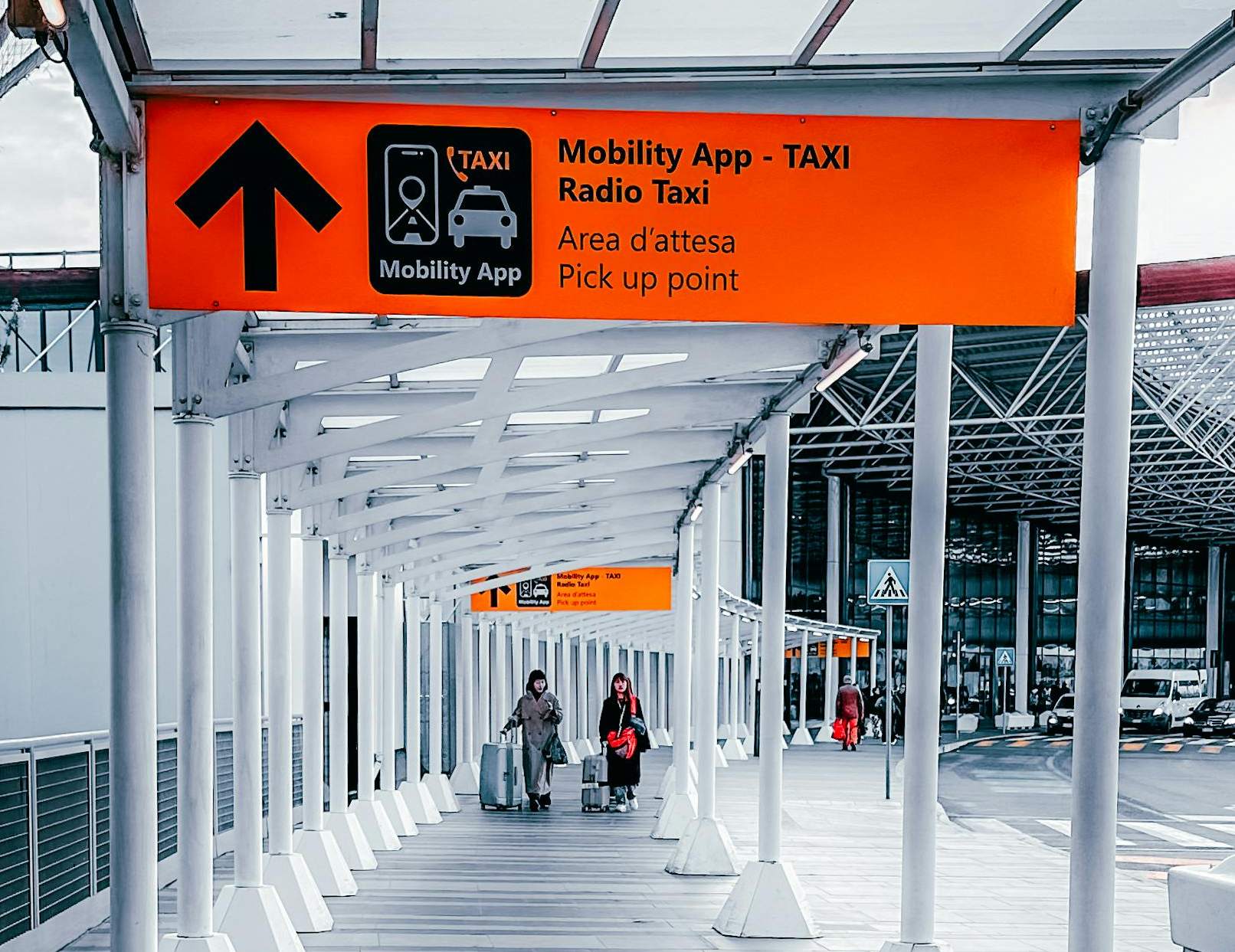 A sign indicating "taxi" alongside a sign for "mobility app," highlighting the importance of pre-booked airport transfers.