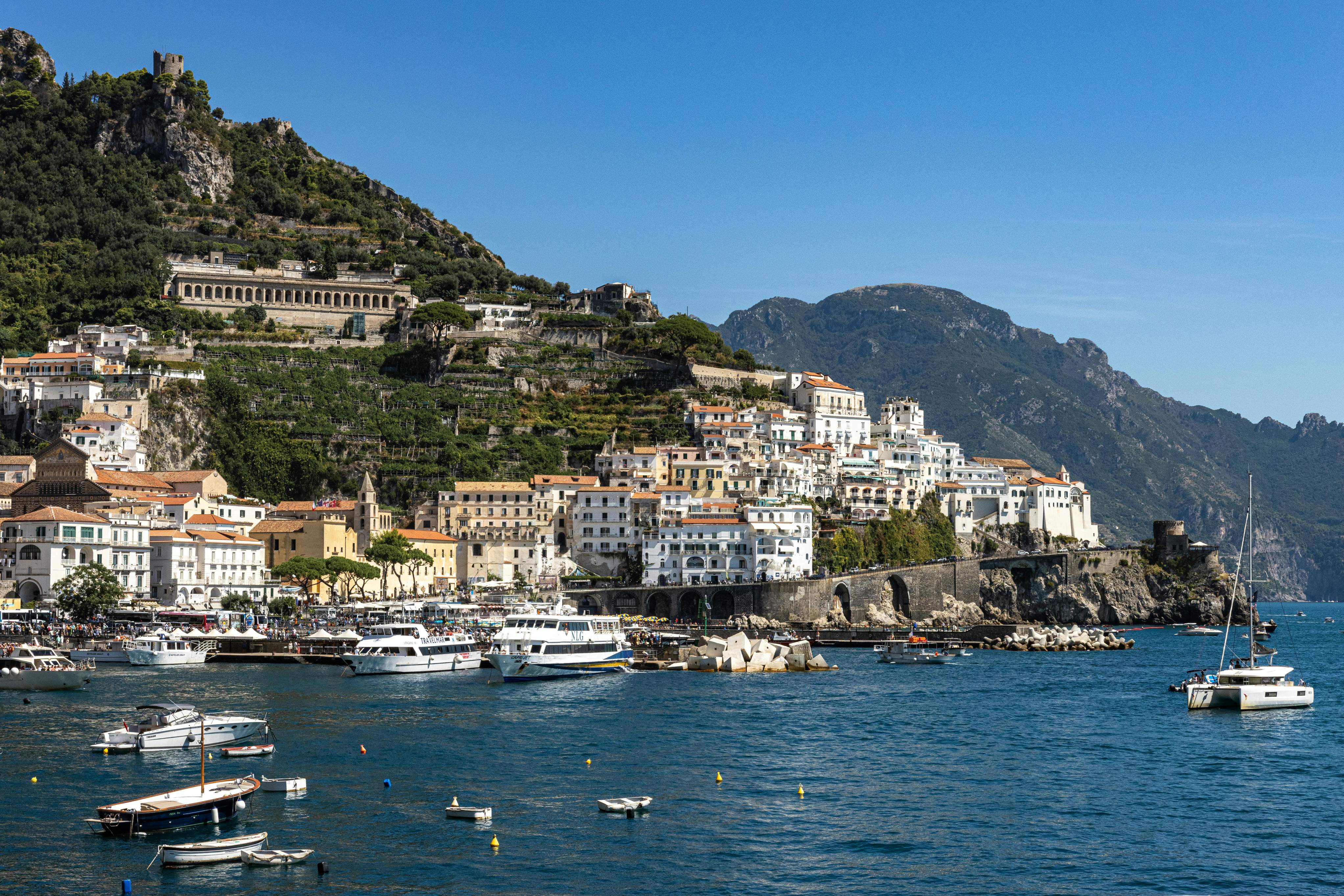 A scenic view of Amalfi, Italy, showcasing colorful buildings along the coast with a ferry in the foreground.