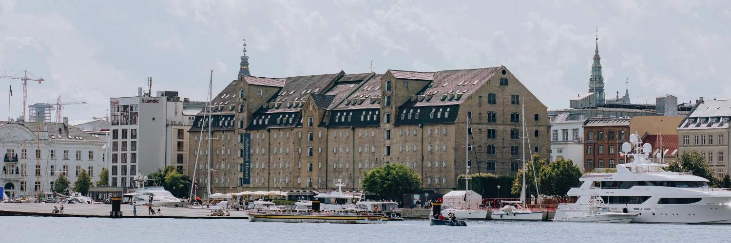 A scenic view of Copenhagen's harbor, featuring buildings and a boat, showcasing the city's vibrant waterfront.