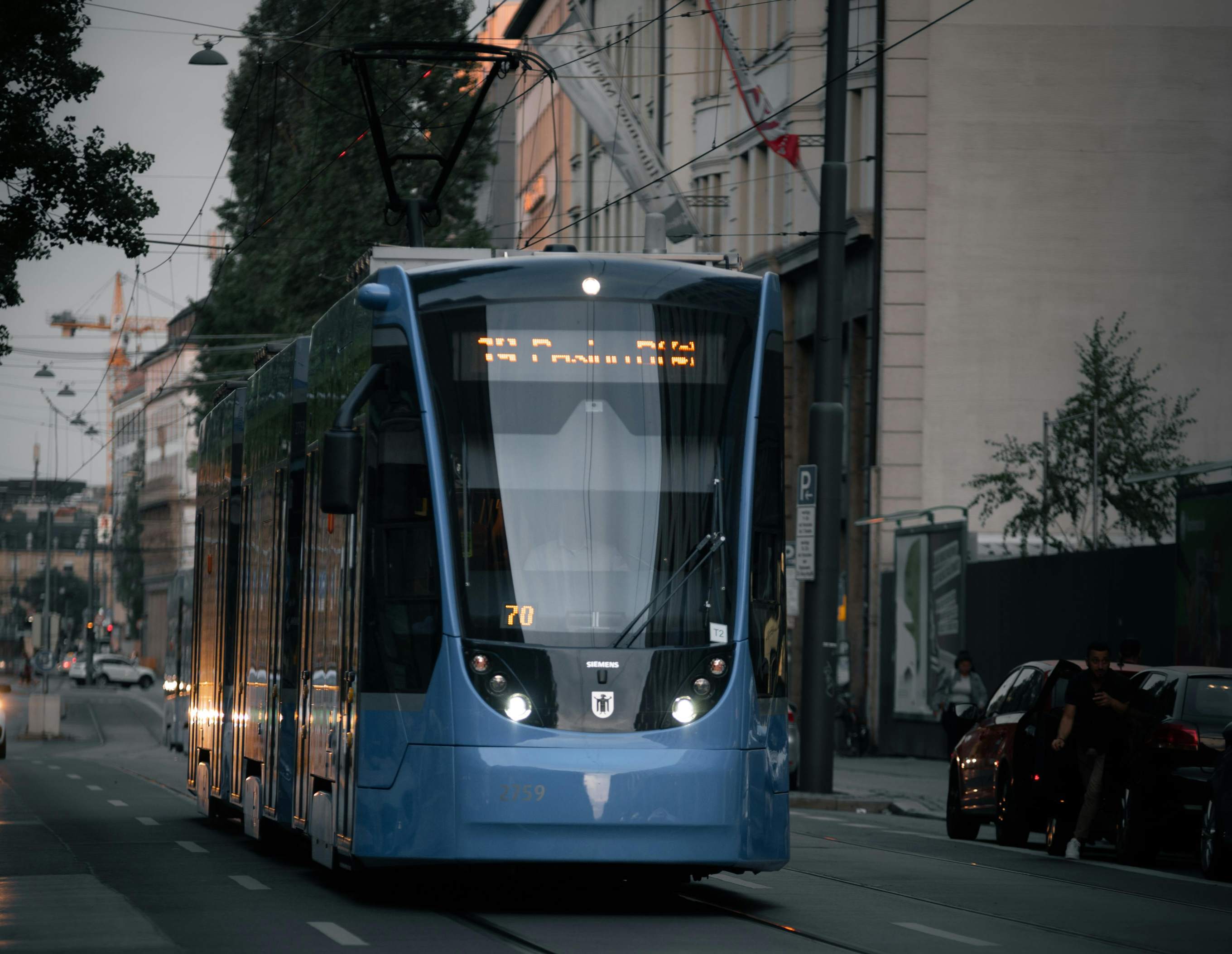Modern blue Munich tram service traveling through a city street during evening hours in Munich, Germany.
