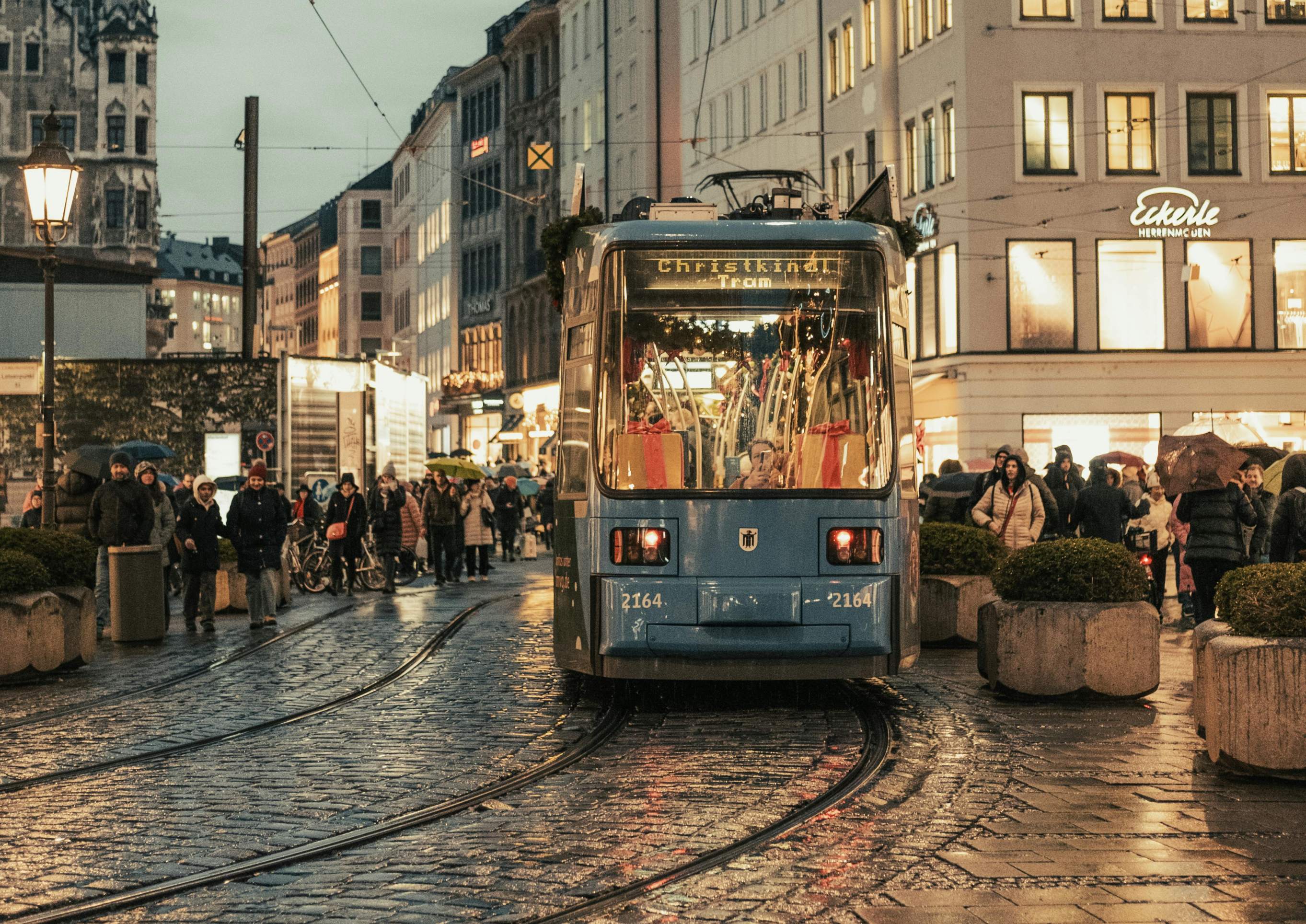 A Munich tram travels along a cobblestone street, showcasing the city's historic charm and urban transport.