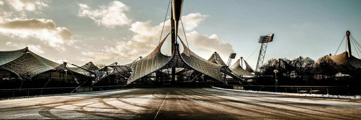 The Munich Olympic Park features a prominent building adorned with numerous tents, indicating a lively gathering or event.
