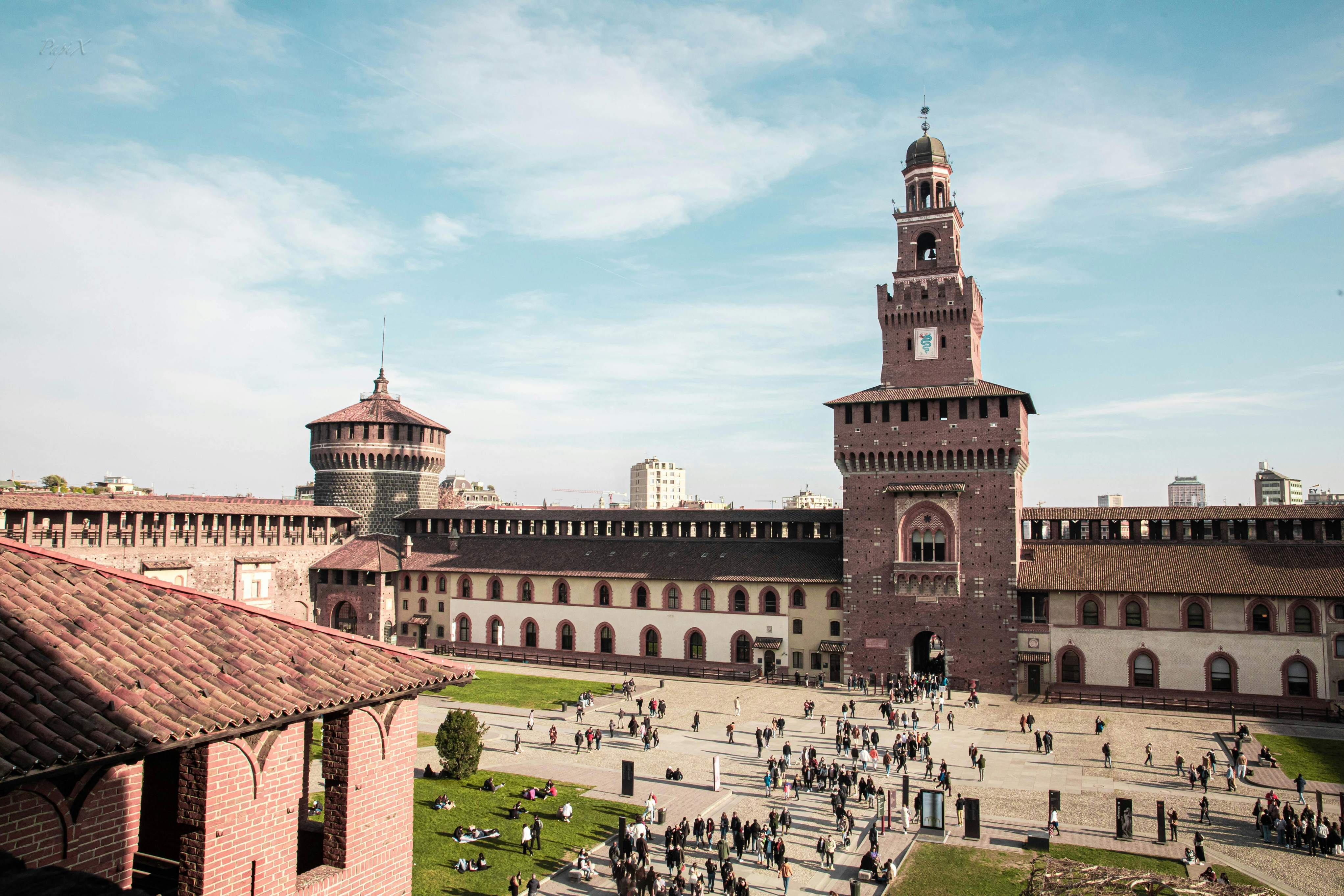 Sforza Castle in Milan, featuring a prominent clock tower and a spacious courtyard.