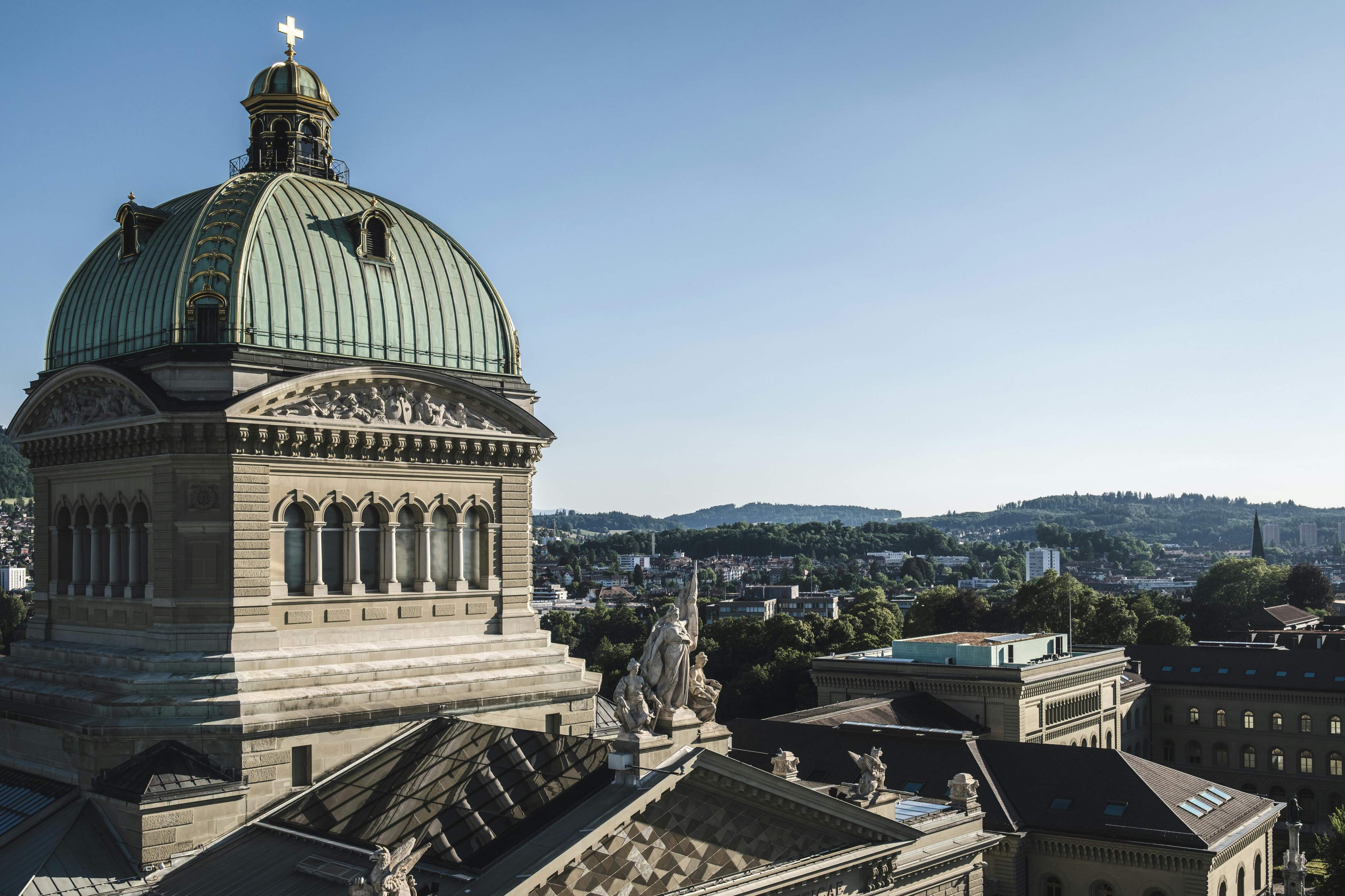 The Swiss Parliament Building in Bern, showcasing its distinctive dome and elegant facade against a clear sky.