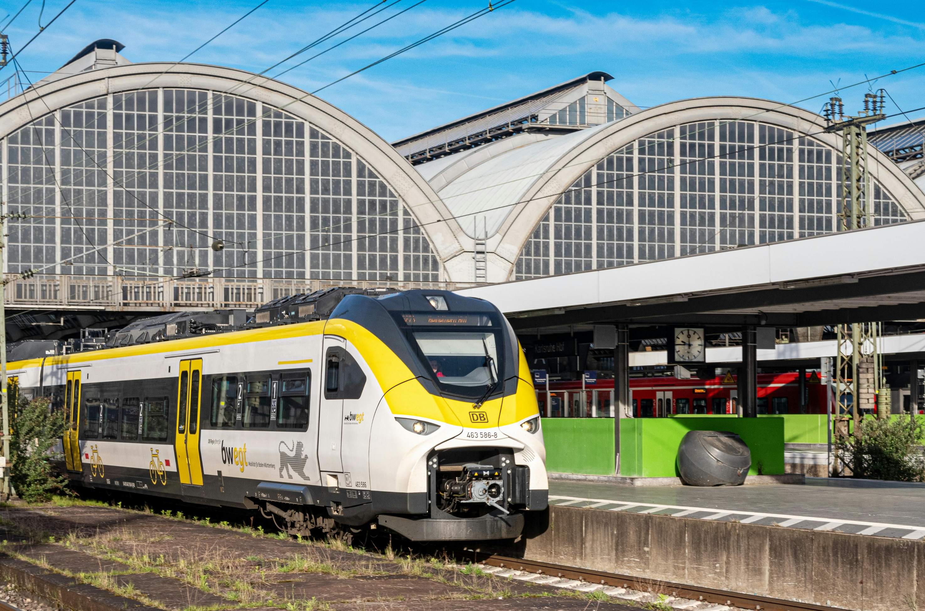 A yellow and white train parked at a station in Munich, showcasing its vibrant colors against the urban backdrop.
