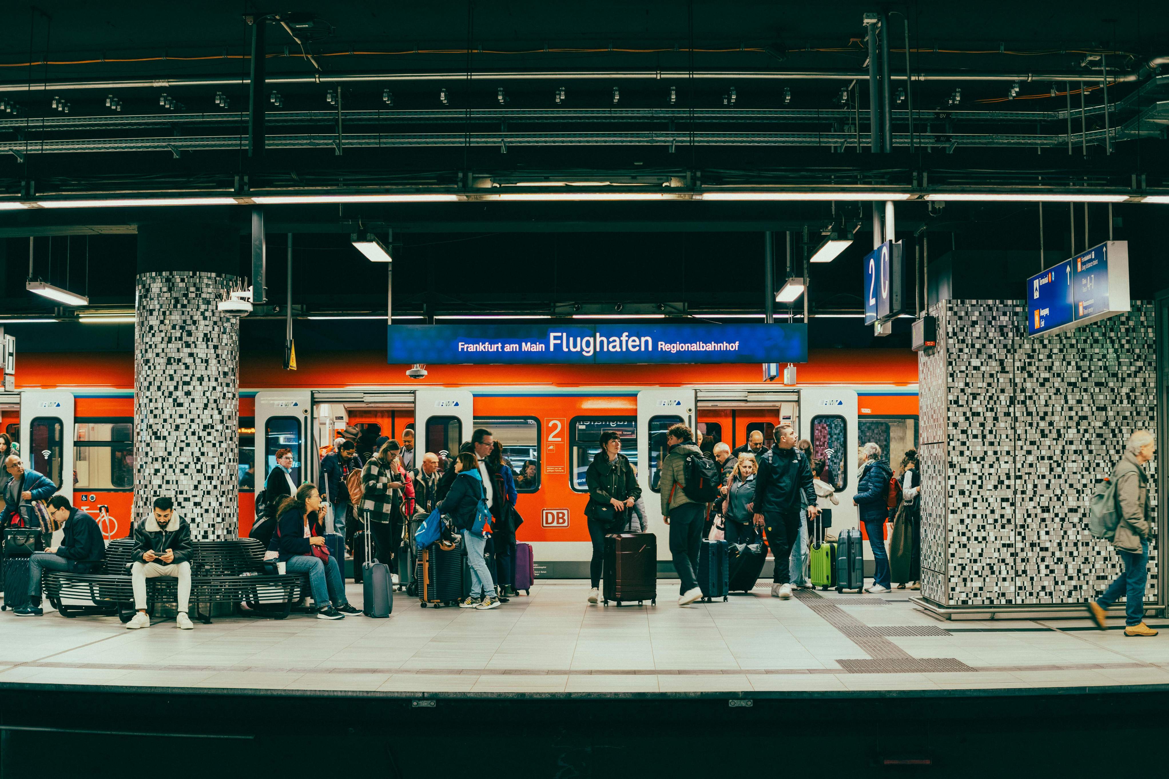 A lively Frankfurt train station scene featuring travelers waiting for their trains on a bustling platform.