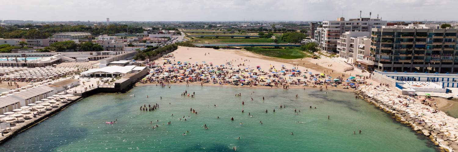 A panoramic view of Bari Beach, showcasing a large, tranquil body of water under a clear blue sky.