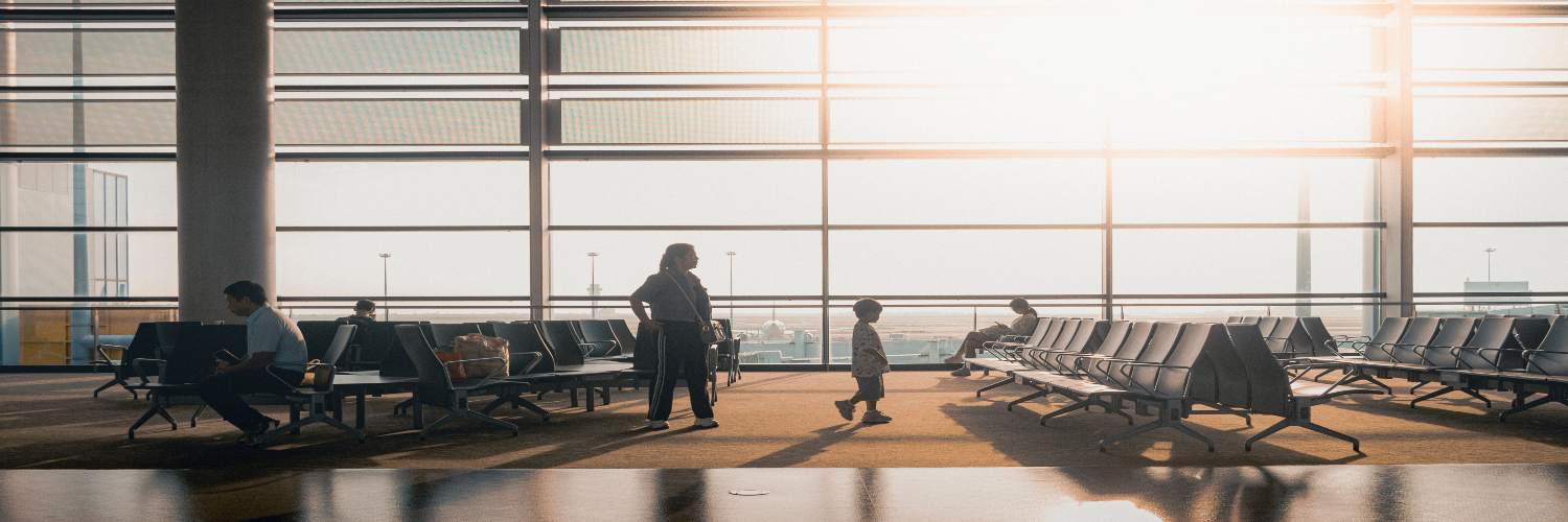People relax in a bright airport waiting area, enjoying the sunlight as they await their family transfer.