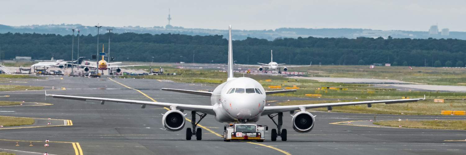 A large passenger jet taxiing on the runway at Frankfurt Airport, with terminal buildings in the background.