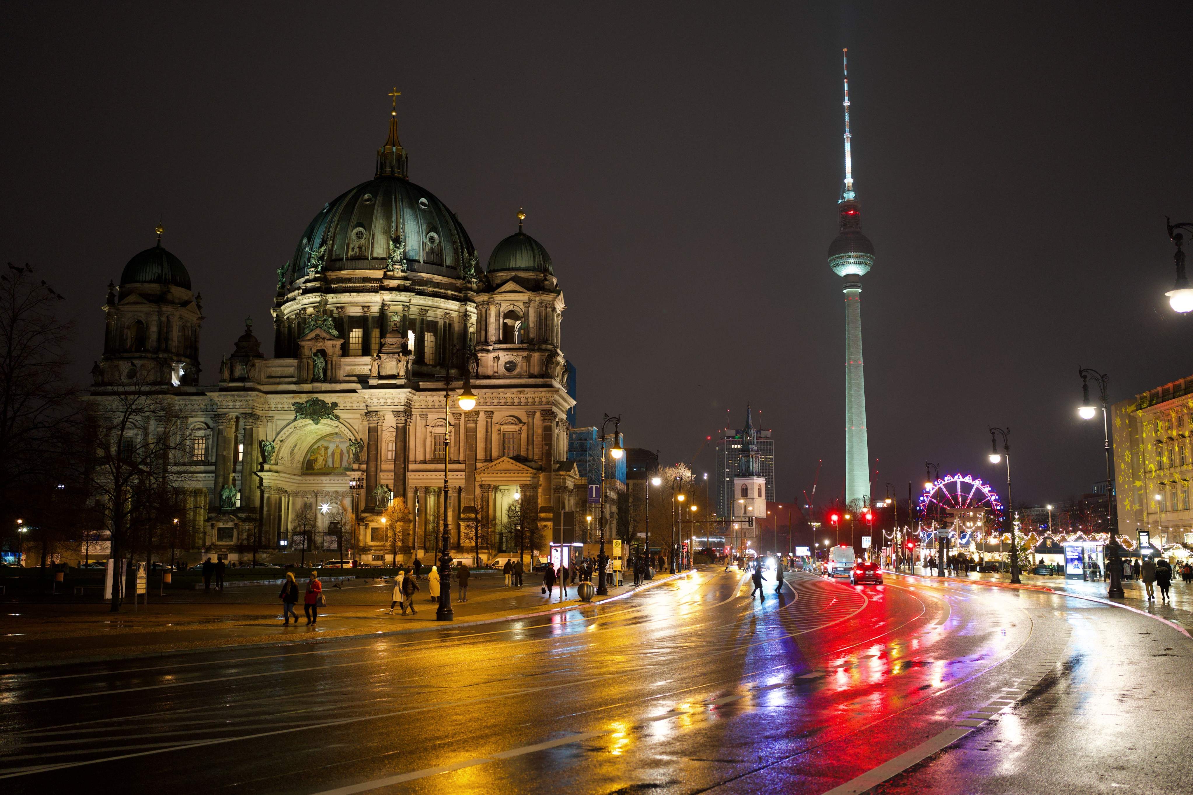 Berlin Cathedral with its large dome and the Fernsehturm tower in the background against a clear blue sky.