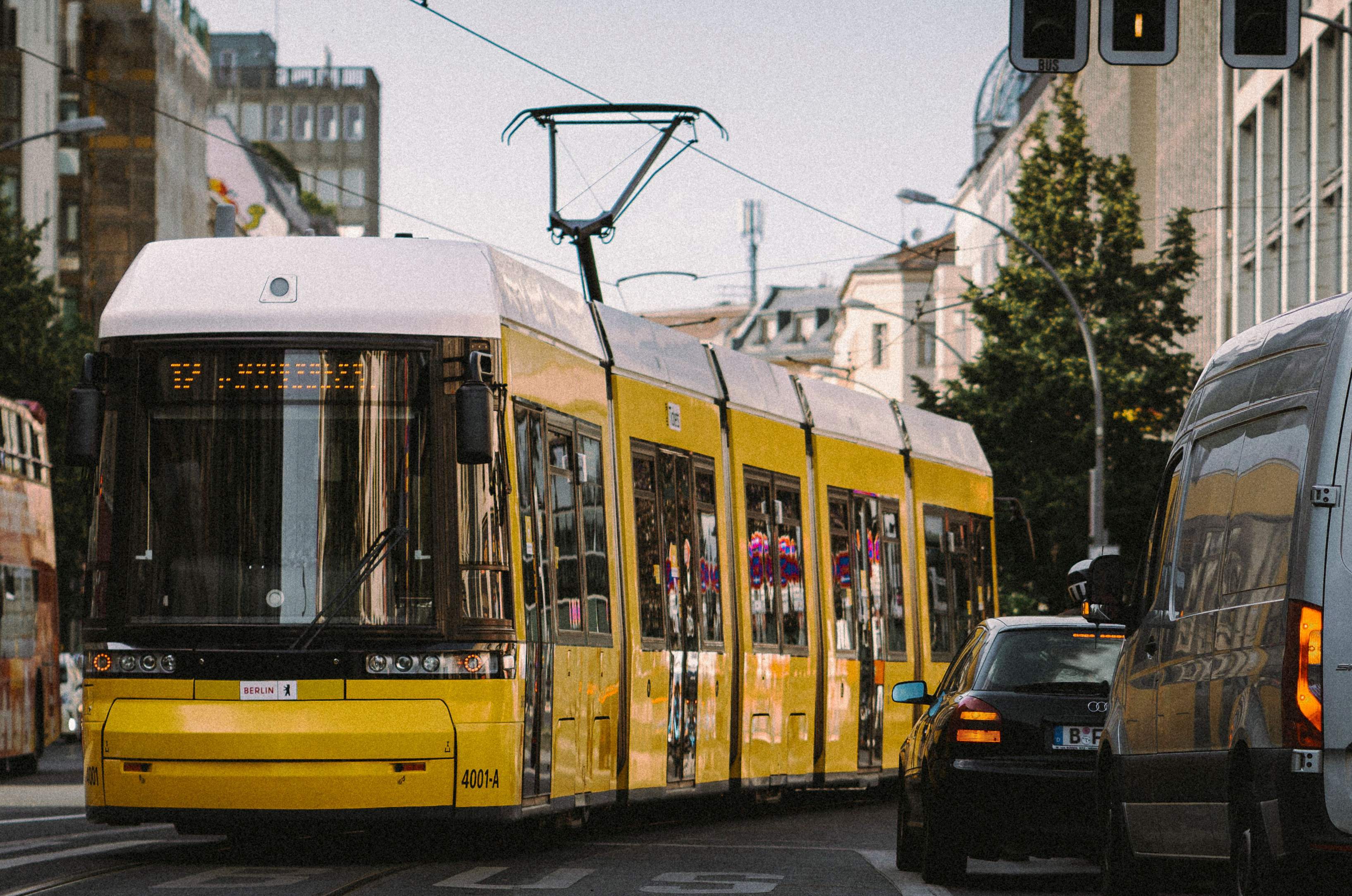 A yellow and white tram in Berlin, showcasing the city's public transportation system against an urban backdrop.