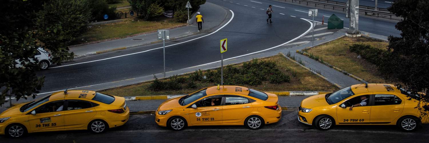 Three yellow taxis parked along the roadside, ready for passengers in an urban setting.