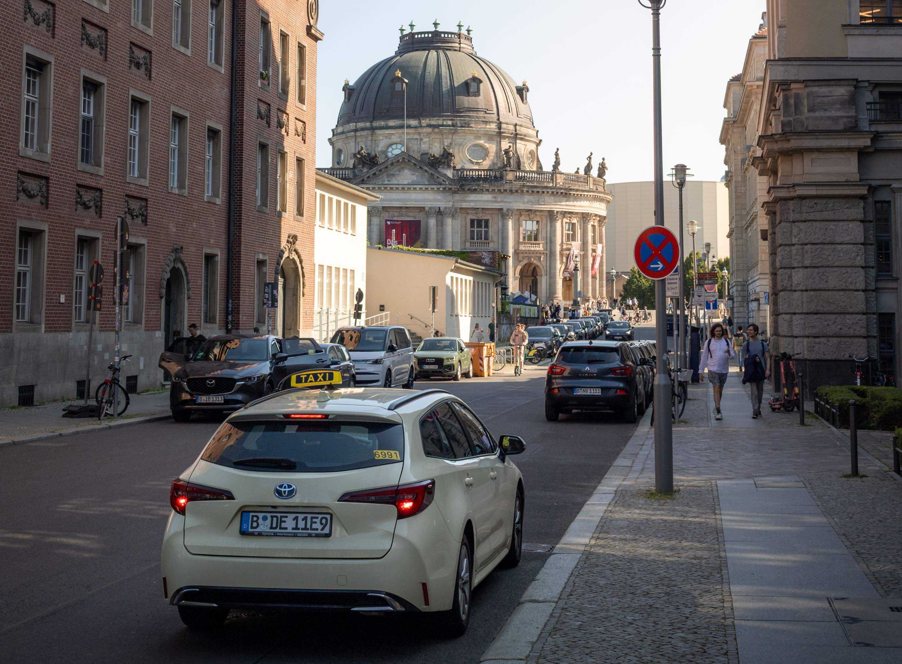A car driving along a city street with a modern building visible in the background, representing Berlin transfer services.